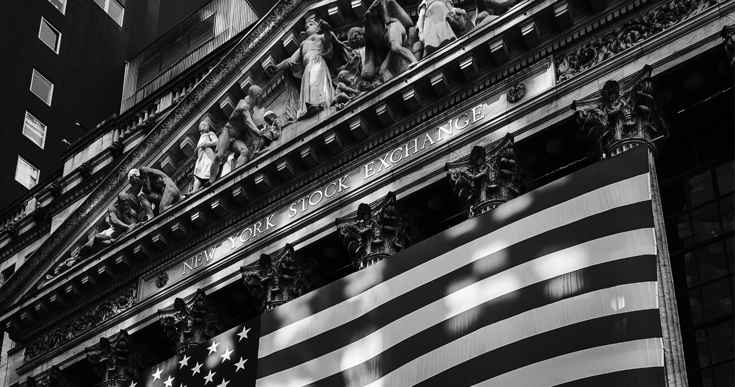 The facade of the New York Stock Exchange, an American flag hung between its columns